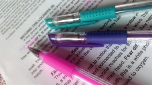 Colored pens against a page of text with editing marks